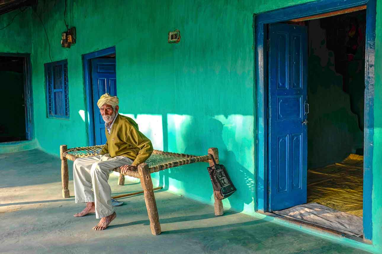 Elderly man seated on a traditional charpoy in rural North India